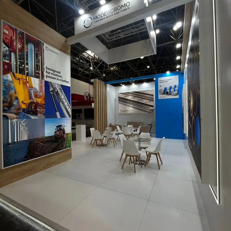 Heller Messestand mit Holzverkleidung, blauen Wandgrafiken und weißen Sitzgruppen.