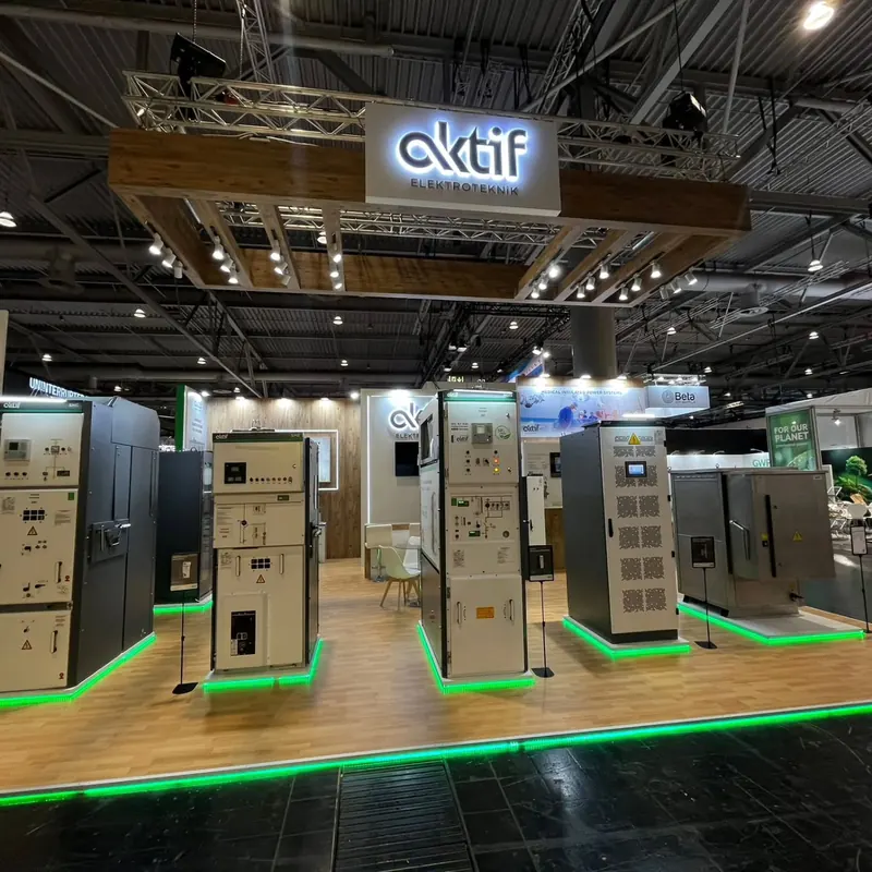 Schwarz-weißer Messestand mit hohen Produktpodesten, grün beleuchteten Bodenkanten und Holz-Deckenrahmen.