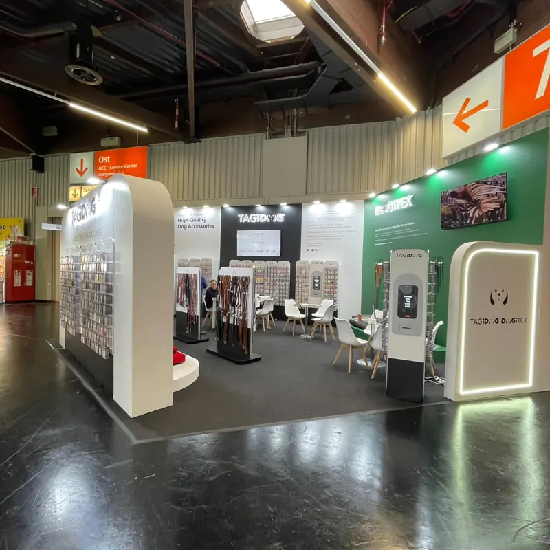 Messestand mit abgerundeten weißen Wänden, grüner Rückwand und freistehenden Produktdisplays.