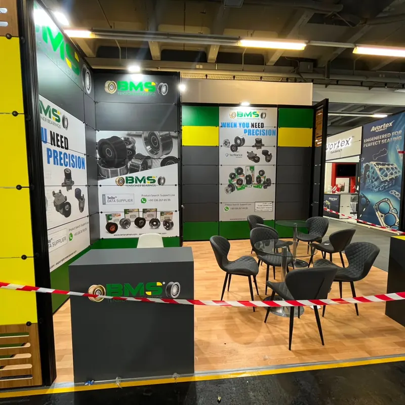Schwarz-grüner Messestand mit Produktgrafiken, Holzoptikboden und runder Sitzgruppe.