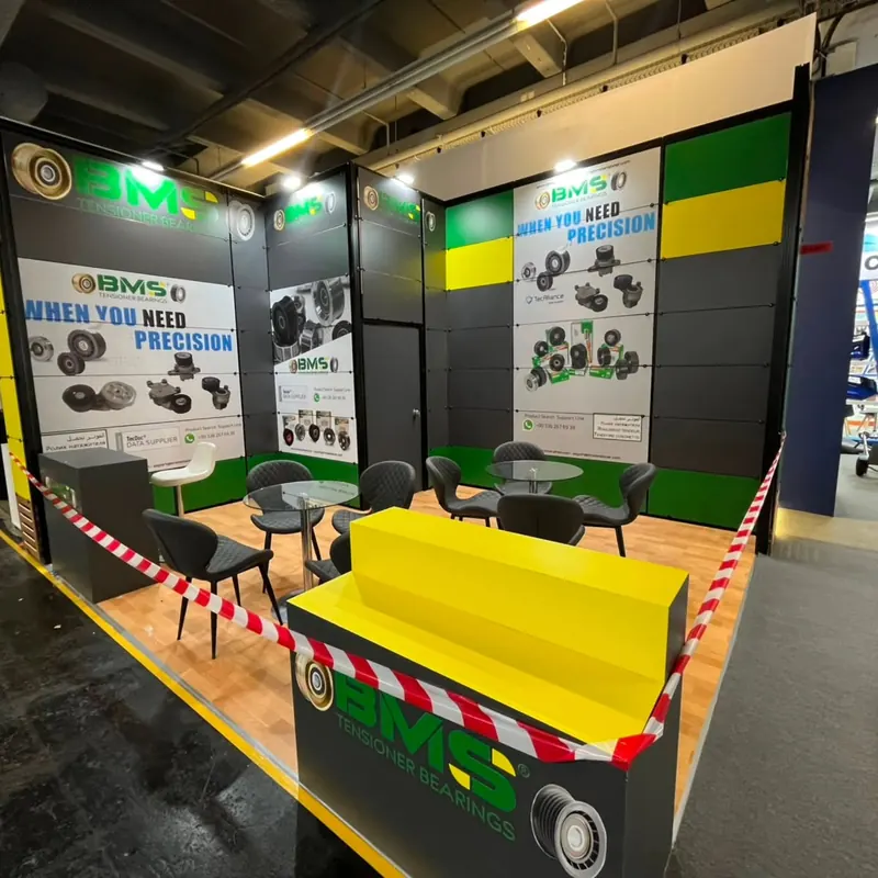 Grün-schwarzer Messestand mit gelbem Stufendisplay und schwarzen Sitzgruppen.