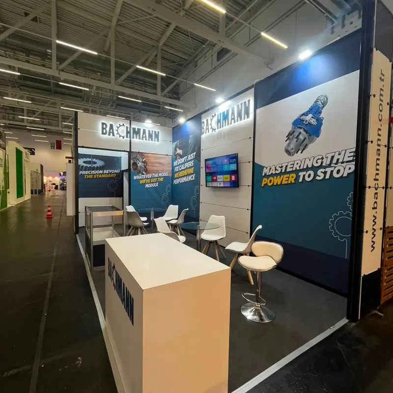 Blau-weißer Messestand mit Empfangstheke und weißen Barhockern.