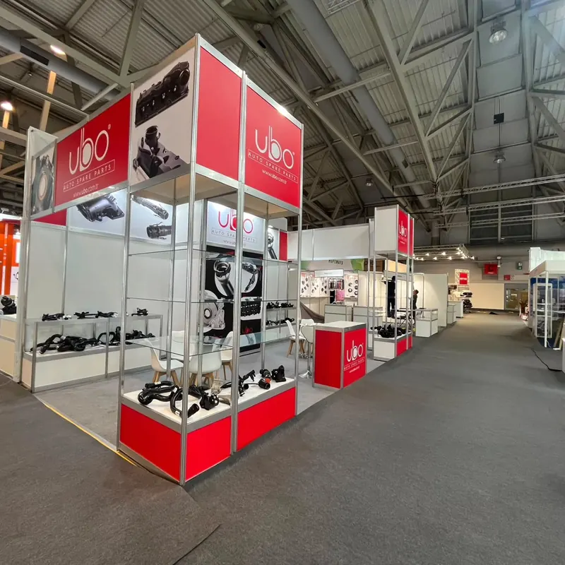 Rot-weißer Messestand mit hohen Glasvitrinen und dunklen Produktteilen.